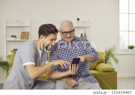 Happy senior man and caregiver using smartphone, looking at photos, and having fun Happy senior man and caregiver using smartphone, looking at photos, and having fun 131459467