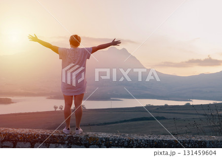 Sunrise travel moment, arms raised above mountain valley and calm lake landscape Sunrise travel moment, arms raised above mountain valley and calm lake landscape 131459604