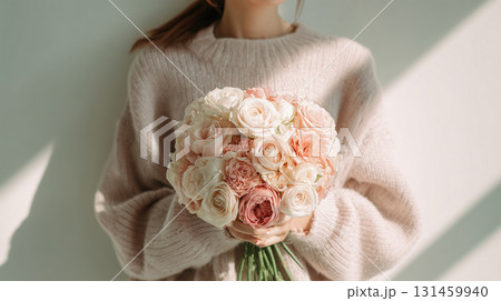 女性が淡いセーターでバラの花束をそっと持つ 131459940