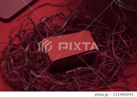 Blank red business cards in decorative nest of red raffia 131460043