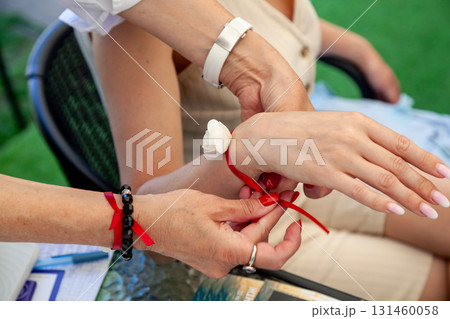 Tying a symbolic red ribbon bracelet on womans wrist Tying a symbolic red ribbon bracelet on womans wrist 131460058