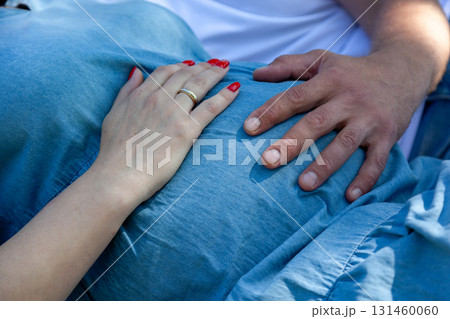 Hands of expecting parents gently touching pregnant belly Hands of expecting parents gently touching pregnant belly 131460060