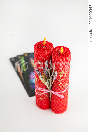 Decorative red candles with dried flowers and tarot cards displayed on a white background 131460347