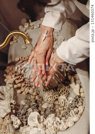 Young woman with pearls washes hands in a decorative seashell washbasin 131460374