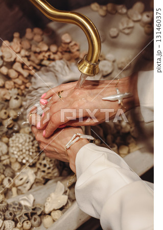 Hands cleansing with flowing water over decorative stones in a serene setting Hands cleansing with flowing water over decorative stones in a serene setting 131460375