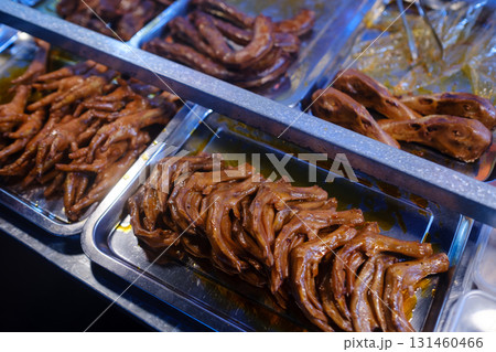 Deliciously cooked chicken feet served in various sauces at a busy street market during the evening Deliciously cooked chicken feet served in various sauces at a busy street market during the evening 131460466