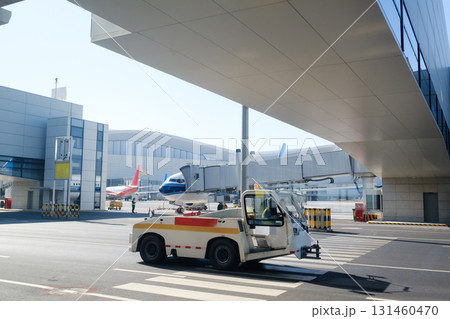 Busy airport scene with aircraft and ground support vehicle under clear blue sky in the afternoon 131460470