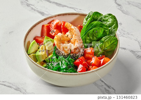 Poke bowl with salmon, shrimp, chuka seaweed, tomatoes, avocado, and spinach leaves 131460823