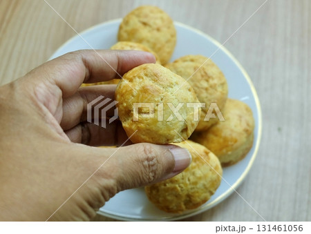 Hand Grabbing Crispy Golden Scone, Ready-to-Eat Snack 131461056