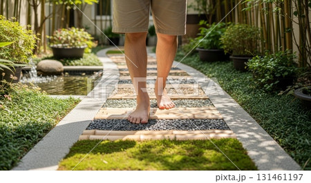 Person walking barefoot on therapeutic reflexology stone path with wooden planks and pebbles in zen garden landscape design 131461197