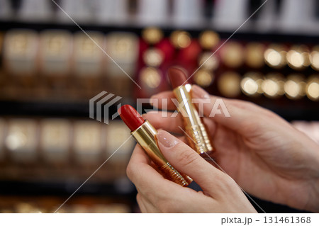 A woman is gracefully holding a bright red lipstick in her hand A woman is gracefully holding a bright red lipstick in her hand 131461368