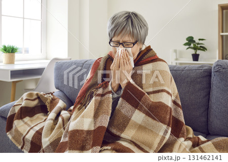 Unhappy frozen mature woman sick at home and suffering from rhinitis, cold and influenza. Unhappy frozen mature woman sick at home and suffering from rhinitis, cold and influenza. 131462141