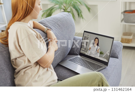 Sick young woman listening recommendations having online video call with a doctor at home. 131462164