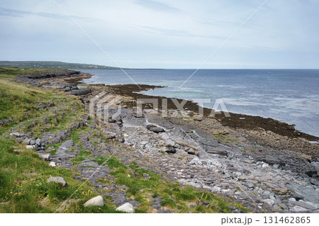 Coastal landscape in Ireland featuring rocky shoreline and ocean under a cloudy sky. Coastal landscape in Ireland featuring rocky shoreline and ocean under a cloudy sky. 131462865