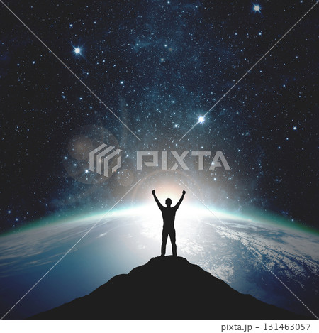Silhouette of a man with raised hands against the backdrop of the planet and sunset. Elements of this image furnished by NASA 131463057