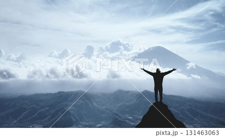 Silhouette of a jubilant man on the peak of a mountain, concept of victory and achievement Silhouette of a jubilant man on the peak of a mountain, concept of victory and achievement 131463063