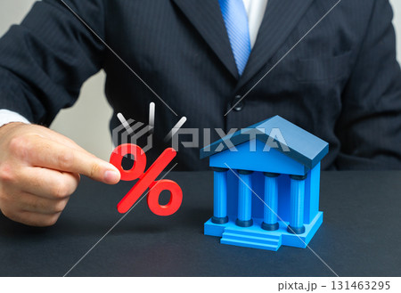 A businessman holds interest near a bank building. Inflation and deposits. Concept of capital growth, monetary risks, savings, loans, economic policy, investments and financial stability. 131463295