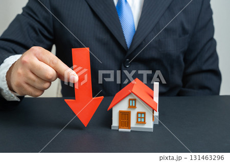 The businessman notes a fall in housing prices. Symbol of real estate market decline, mortgages, property devaluation, economic crisis, investments, banking and financial risks. 131463296