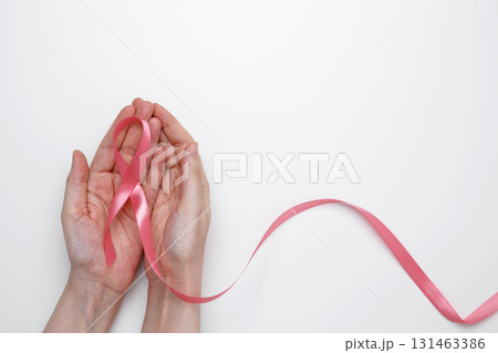 Female hand holding pink ribbon symbol of breast cancer awareness Female hand holding pink ribbon symbol of breast cancer awareness 131463386
