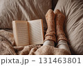 Girl on bed with open book and wool socks 131463801