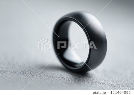 Modern matte black smart ring with integrated biometric sensors on finger close-up Modern matte black smart ring with integrated biometric sensors on finger close-up 131464096