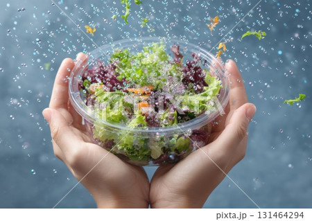 Hands holding container with fresh salad and floating plastic microbeads showing contamination risk 131464294