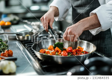Chef preparing meal using local organic vegetables in stainless steel kitchen highlighting real textures 131464335