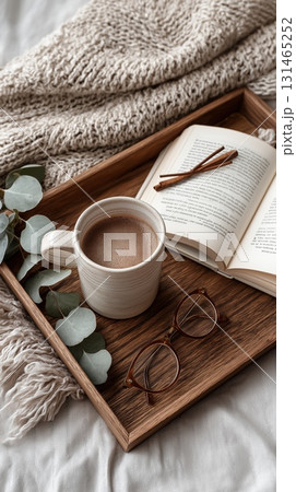 Top-down view of a tray with hot chocolate, book and glasses on a knitted blanket 131465252