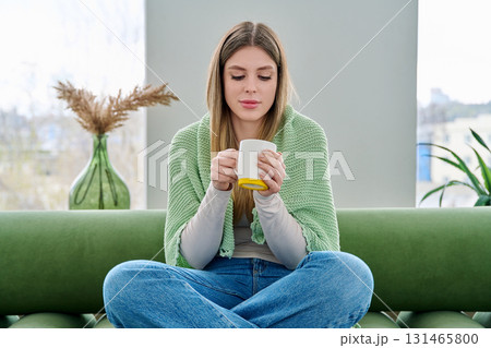 Portrait of relaxed beautiful young woman sitting at home on sofa with cup Portrait of relaxed beautiful young woman sitting at home on sofa with cup 131465800