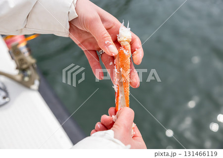woman opens leg of freshly caught crab on boat 131466119