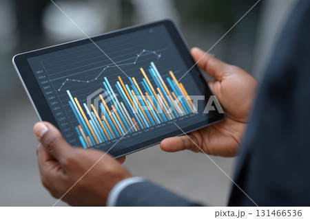 Person presenting a detailed graph on a tablet during a business meeting in a modern office setting 131466536