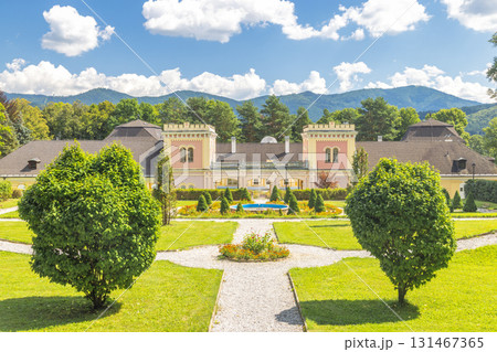 Hodkovce Mansion in Zehra village in Slovakia, Europe. Stately manor house nestled in a lush green park with a mountain backdrop under a clear blue sky filled with fluffy white clouds. Hodkovce Mansion in Zehra village in Slovakia, Europe. Stately manor house nestled in a lush green park with a mountain backdrop under a clear blue sky filled with fluffy white clouds. 131467365