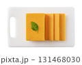 Sheddar cheese slices on a chopping board cutout.  131468030