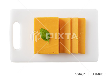 Sheddar cheese slices on a chopping board cutout.  131468030