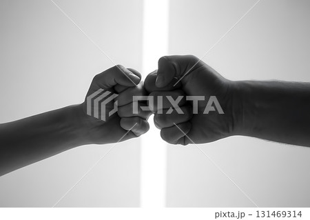 Two fists bumping together in a monochrome image against a bright background 131469314