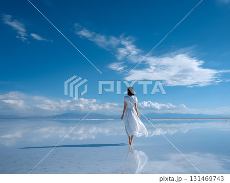 白いワンピースを着た女性が水面を歩く青空の風景ウユニ塩湖のような幻想的な旅や自由を表現 白いワンピースを着た女性が水面を歩く青空の風景ウユニ塩湖のような幻想的な旅や自由を表現 131469743