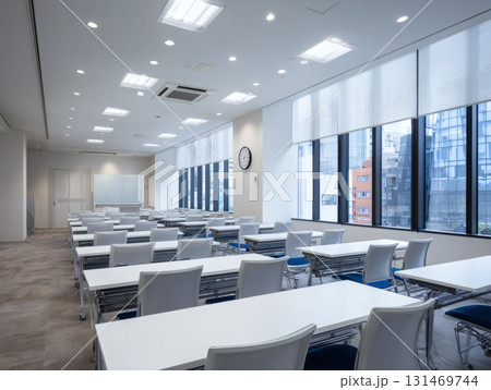 明るい会議室の空のデスクと椅子が並ぶ教室風の室内セミナー研修発表会に使用できるオフィス空間 明るい会議室の空のデスクと椅子が並ぶ教室風の室内セミナー研修発表会に使用できるオフィス空間 131469744