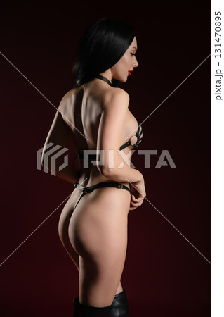 Woman poses confidently in stylish leather accessories in a studio setting 131470895
