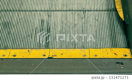 Detailed close-up view of escalator steps with a worn yellow safety marking. Concept of urban transport, mobility, technology, and safety 131471271