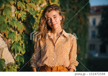Young woman poses outdoors with sunshine illuminating her in a vibrant urban setting 131471594