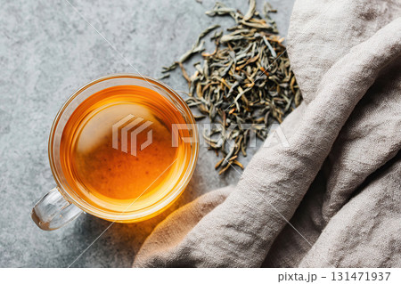 Steeping tea leaves in a clear glass cup for a refreshing beverage experience 131471937