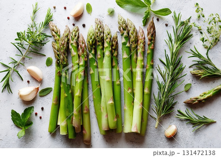 Fresh asparagus spears arranged with herbs and garlic on a light background Fresh asparagus spears arranged with herbs and garlic on a light background 131472138