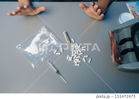 Drug addict male rejecting substances, with pills, syringe, rolled banknote scattered on gray table, symbolizing struggle against addiction and choice for recovery. Concept of healthy lifestyle. Drug addict male rejecting substances, with pills, syringe, rolled banknote scattered on gray table, symbolizing struggle against addiction and choice for recovery. Concept of healthy lifestyle. 131472473