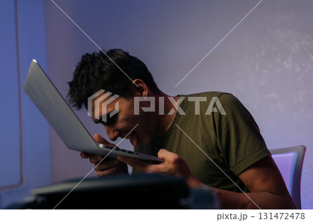 Young programmer male showing extreme frustration by licking laptop after software crash, expressing desperation and anger in humorous way. Frustrated software developer licking laptop keyboard. Young programmer male showing extreme frustration by licking laptop after software crash, expressing desperation and anger in humorous way. Frustrated software developer licking laptop keyboard. 131472478