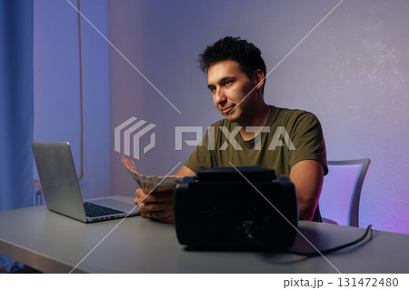 Cashier counting Russian banknotes while working at desk with laptop and money counter machine, illustrating financial accounting in modern office environment. Concept of illegal cash withdrawal 131472480