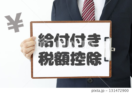 スーツの男性が給付付き税額控除の紙を持つ制度解説イメージ。 131472900