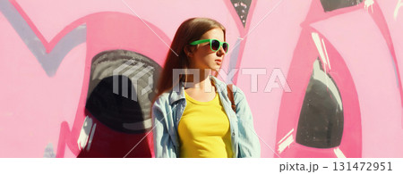 stylish young girl, modern teenager girl looking away posing against background of graffiti wall stylish young girl, modern teenager girl looking away posing against background of graffiti wall 131472951