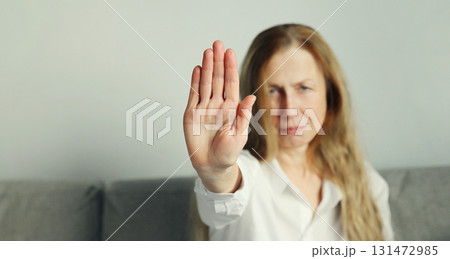 Woman shows stop, no or protest sign with palm of hand, refusal gesture, domestic violence 131472985