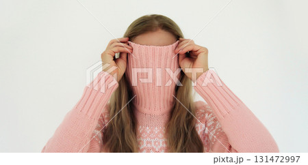 Funny young woman covering her face with knitted sweater or having fun standing on white background Funny young woman covering her face with knitted sweater or having fun standing on white background 131472997