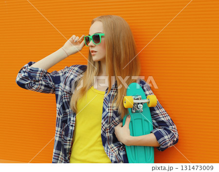 Stylish young woman with skateboard, modern teenage girl posing on city street Stylish young woman with skateboard, modern teenage girl posing on city street 131473009